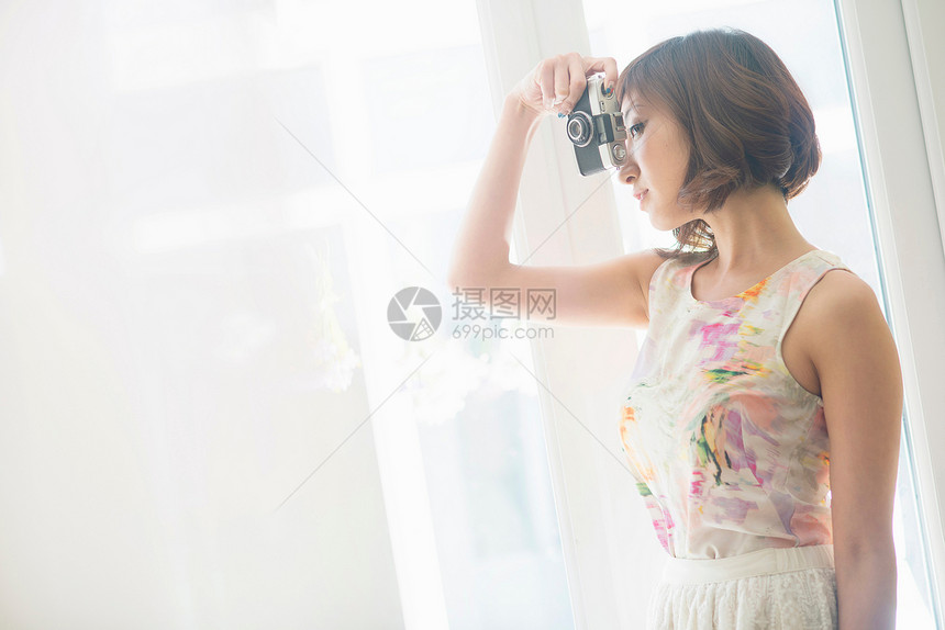 拿着相机拍照的年轻女性图片
