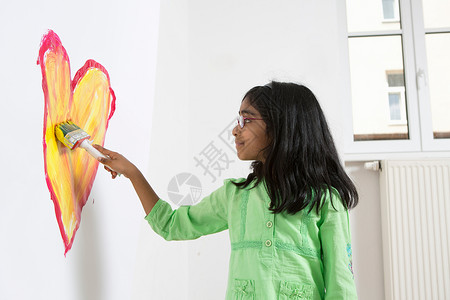 女孩在墙壁上绘画爱心的形状图片