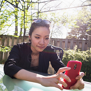 在户外使用红色移动手机的年轻女性图片