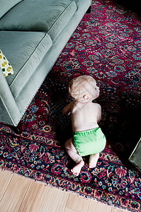婴儿男孩在地毯上爬的俯视图图片