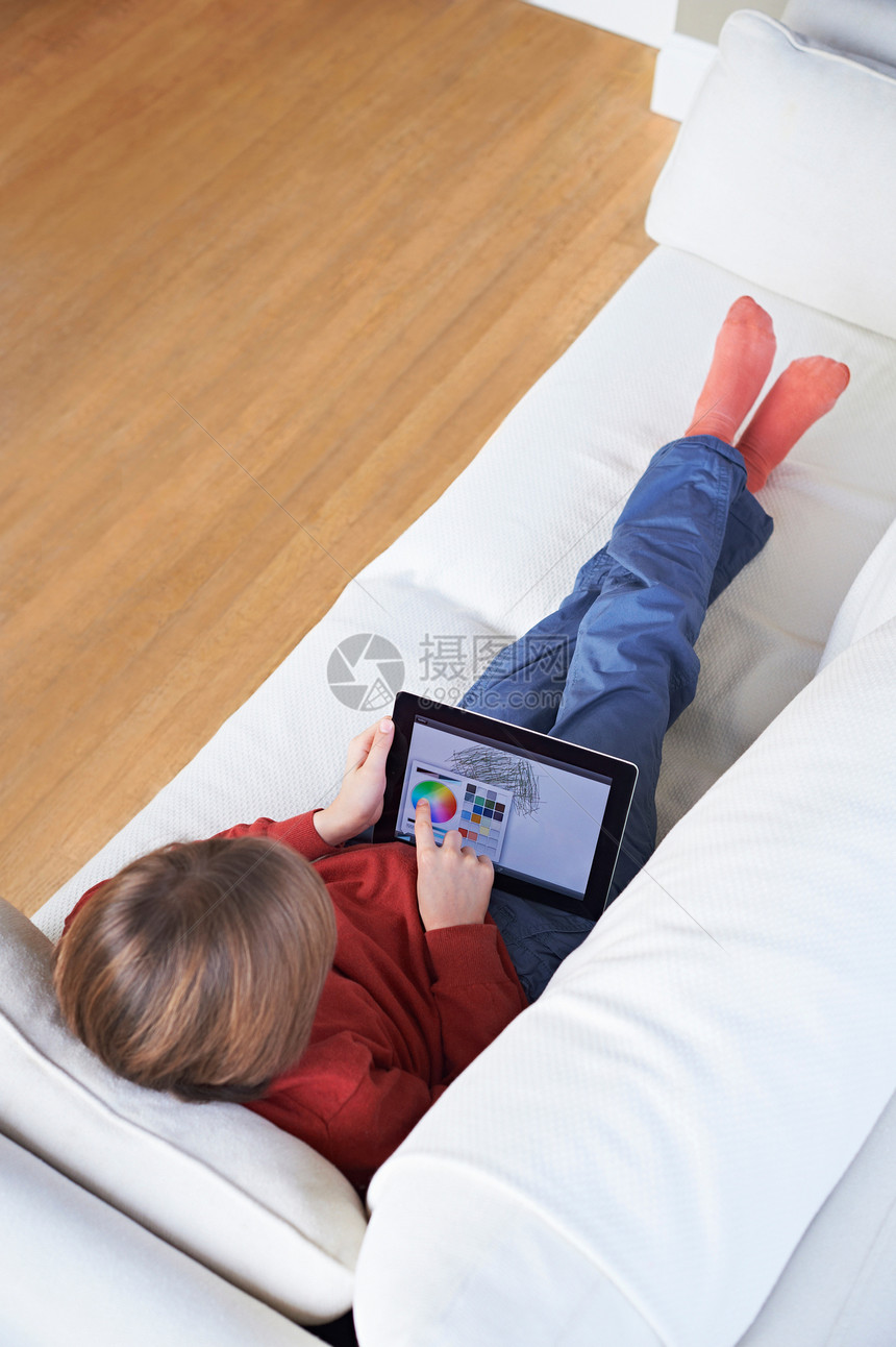 沙发上男孩使用平板电脑图片