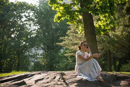 在纽约中央公园使用电话的成年妇女背景图片