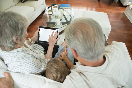 祖父母在沙发上和男孩一起玩平板图片