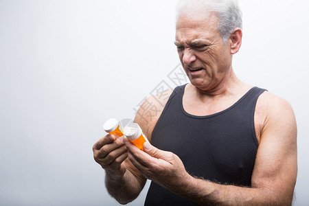 退休老人皱眉看着药瓶图片