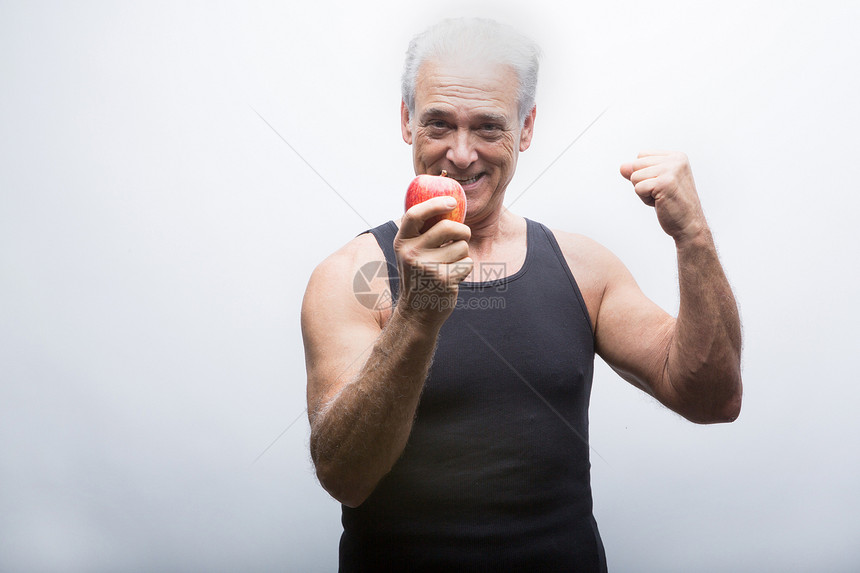 展示肌肉握着苹果微笑的健身男性图片