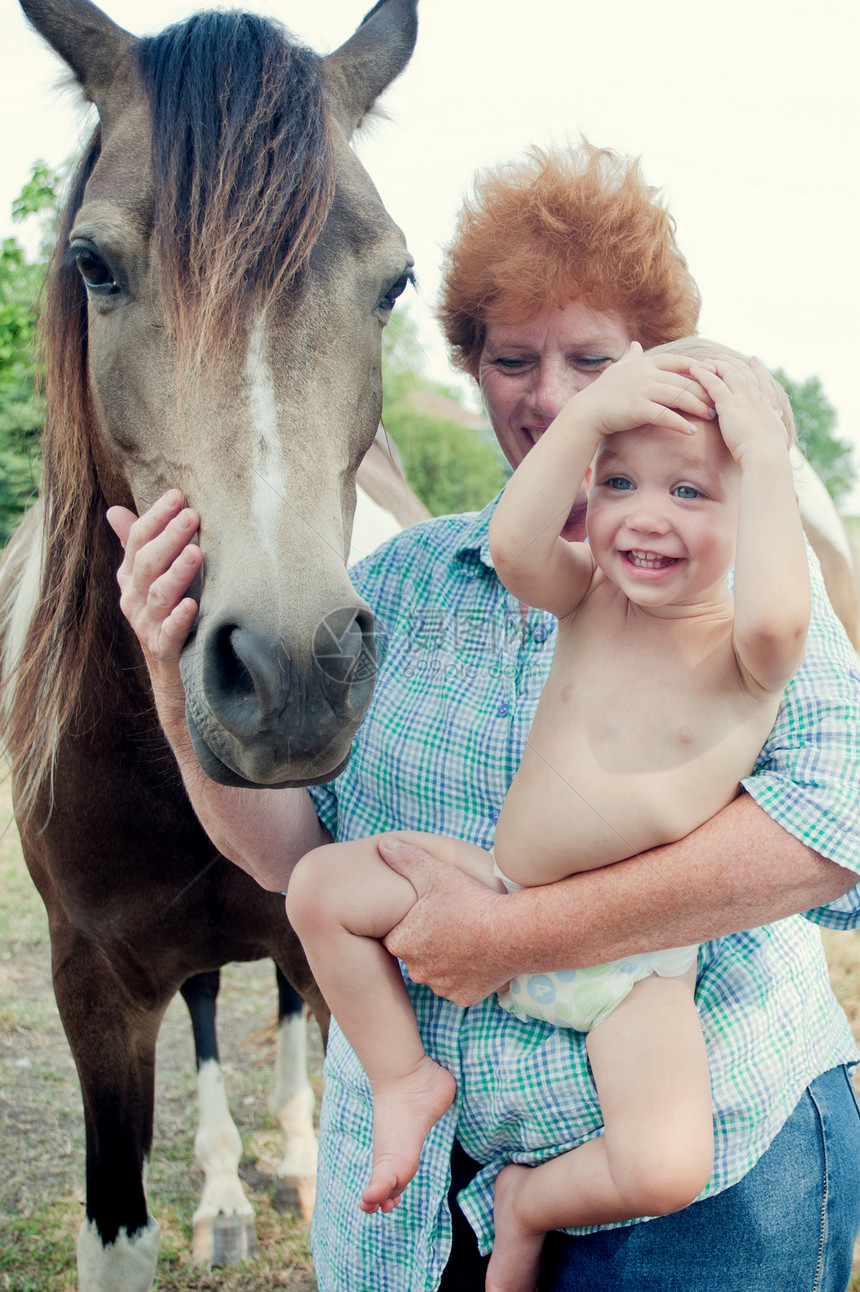 祖母抱着小孩跟马玩耍图片