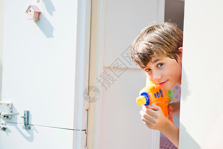 男孩拿着水枪站在门边向外看图片