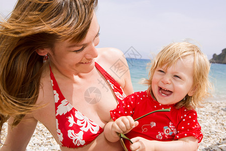 母亲和女儿在海滩微笑图片