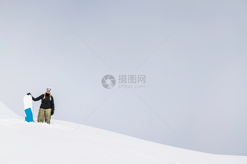 拿着雪板站在雪地上的女运动员图片