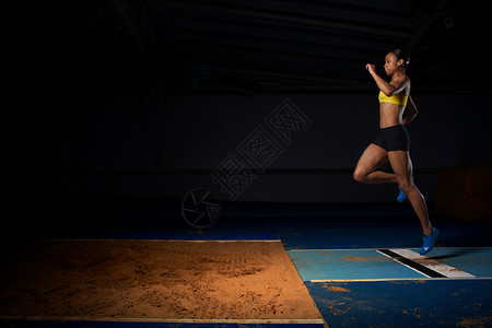 年轻女运动员跳长背景图片