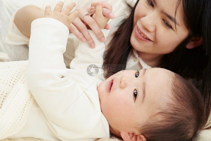 手牵手的母亲和婴儿男孩躺在一起图片