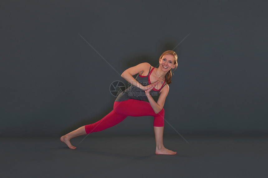 在灰色背景上摆着瑜伽姿势的女性图片