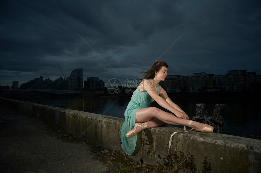 坐在河堤上绑鞋的芭蕾舞者图片