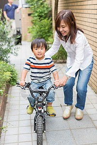 母亲帮助儿子学骑自行车图片