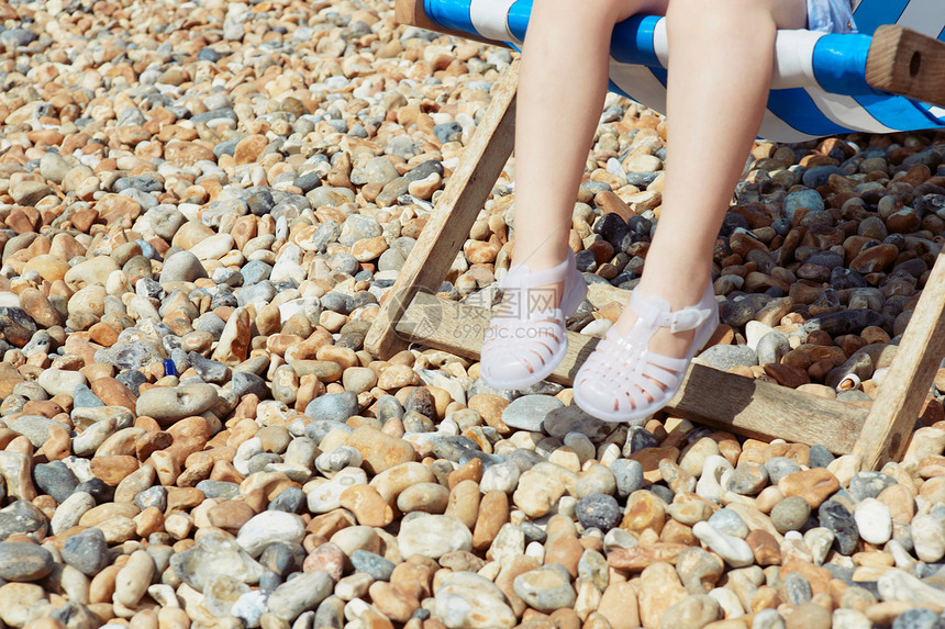 穿凉鞋的小女孩坐在沙滩椅上晒太阳图片