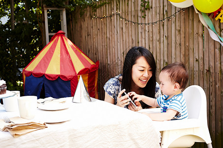 游园会母亲和婴儿一起看智能手机背景