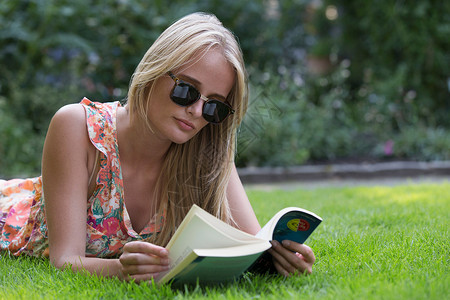 年轻女人在草地上读书图片
