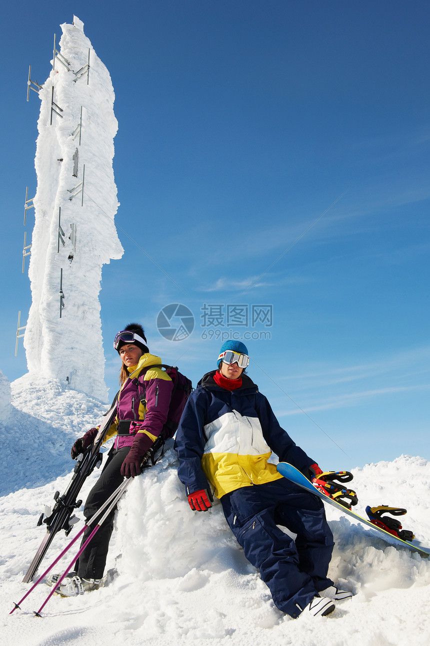 在山顶冰雕前休息的滑雪运动员图片