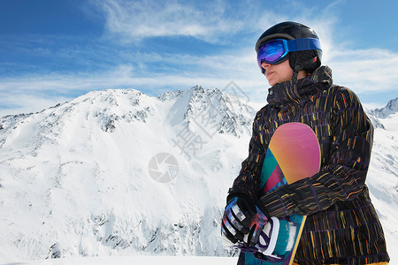 拿着滑雪板站在山顶的女性图片
