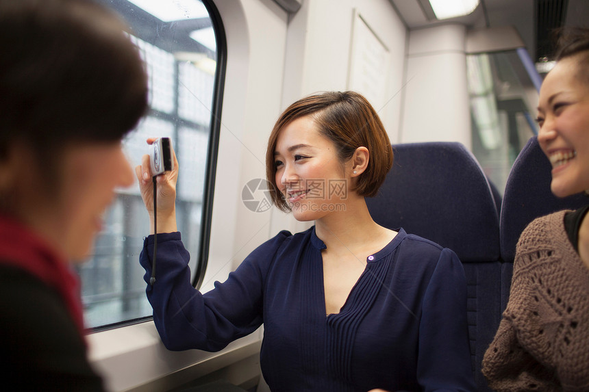 年轻女子与朋友在火车窗口拍照图片