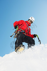 成年男子在雪山上攀岩图片