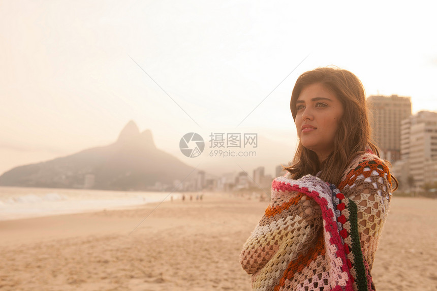 在海滩包着毯子的年轻女性图片