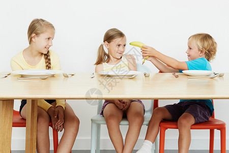 3名儿童坐在桌上男孩拿着香蕉玩耍图片
