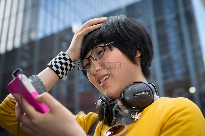 年轻女使用MP3玩家手握头发图片