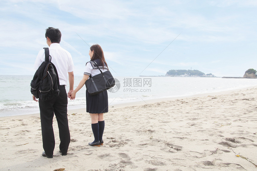 年轻夫妇在海滩上握手图片