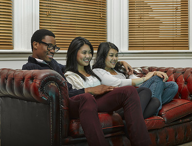三个年轻的成朋友一起坐在沙发上图片
