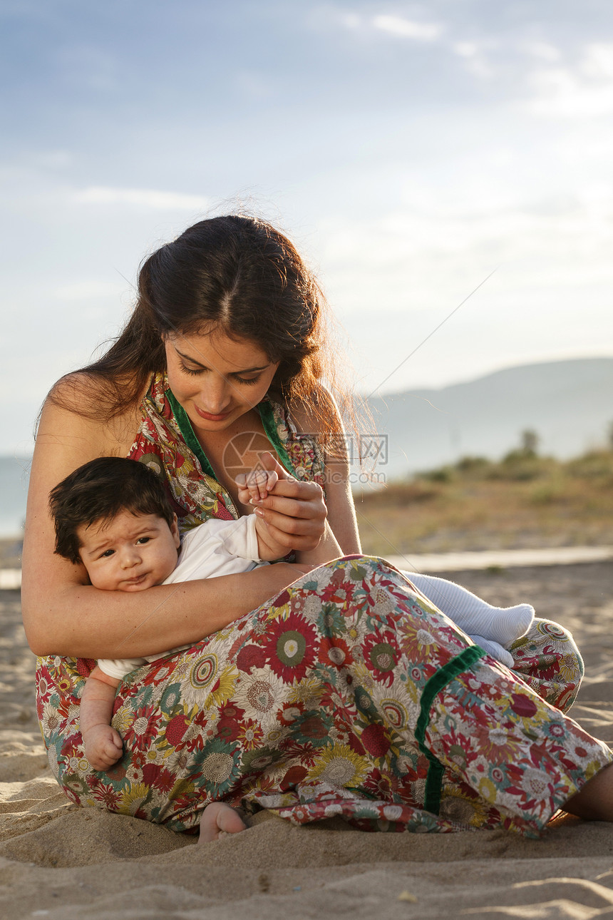 母亲坐在沙滩上抱着婴儿图片