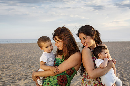 母亲们站在海滩上抱着婴儿高清图片