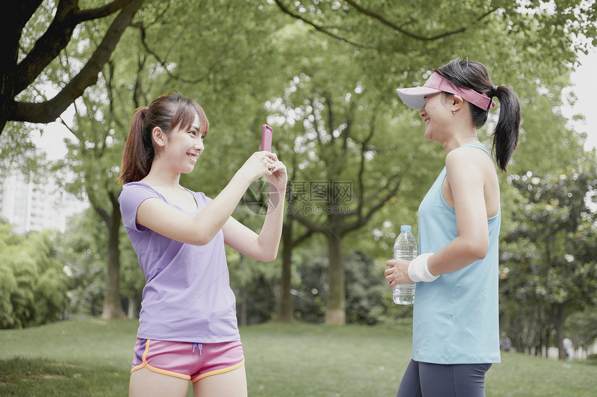 年轻女子在公园给朋友拍照图片