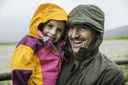 父亲和女儿穿着防雨外套背景图片