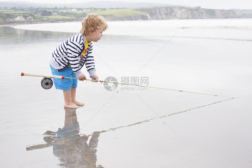 男孩站在海滩上钓鱼图片