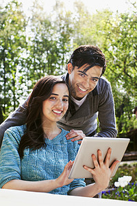 花园里看平板电脑的年轻夫妇高清图片
