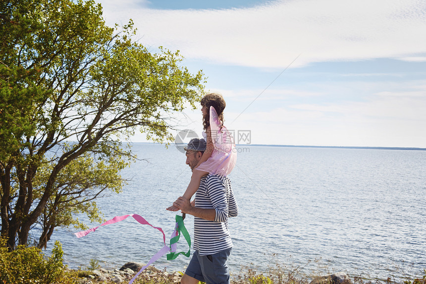 父亲背着女儿在海路上散步图片