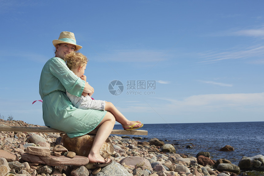 母亲和女儿坐在瑞典埃格隆德的海滩上图片