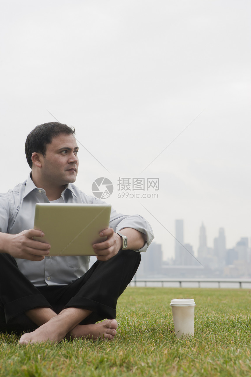 坐在草坪上办公的男人图片