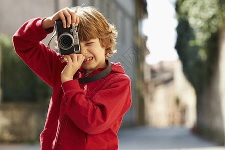 在街上拍摄照片的年轻男孩图片