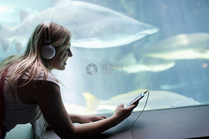在水族馆听音乐的年轻女子图片
