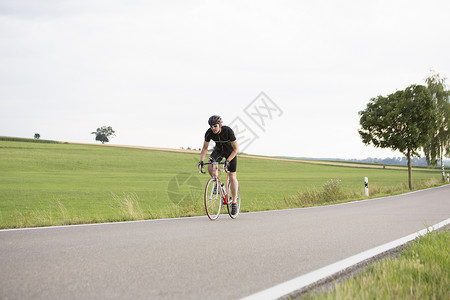 沿乡村公路骑自行车的成年男子图片