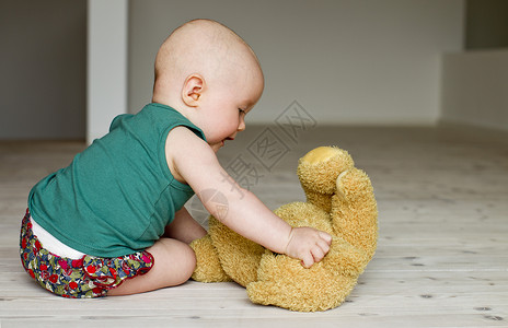 婴儿在地板上玩泰迪熊图片