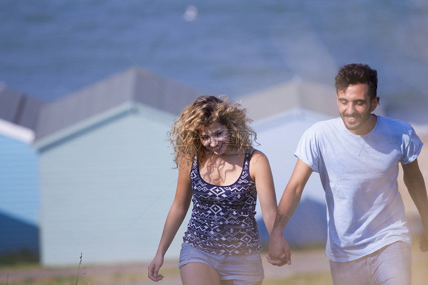 年轻夫妇与背景海滩小屋手牵图片