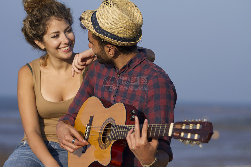 年轻夫妇在海边弹吉他图片