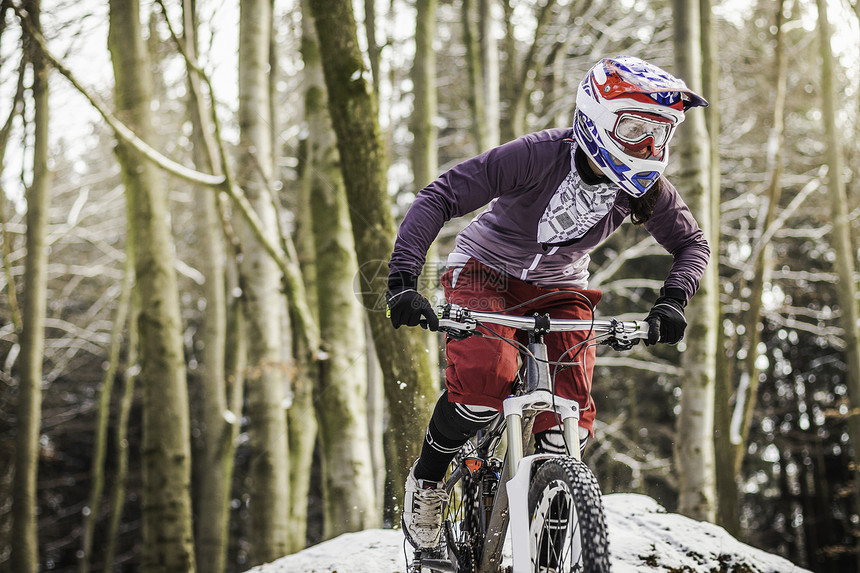 冬季在山上骑自行车的年轻妇女图片