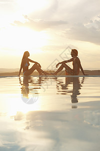 夕阳无限好阳光下坐在无限游泳池边的一对夫妇背景