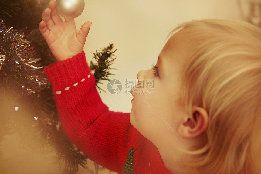 女孩看着圣诞树上的装饰图片