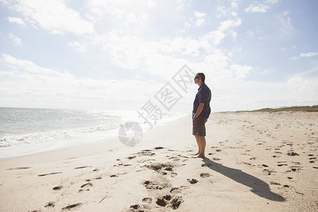 站在沙滩上看海的男性图片