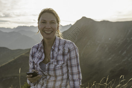 背包客女子在山上玩手机感受大自然图片